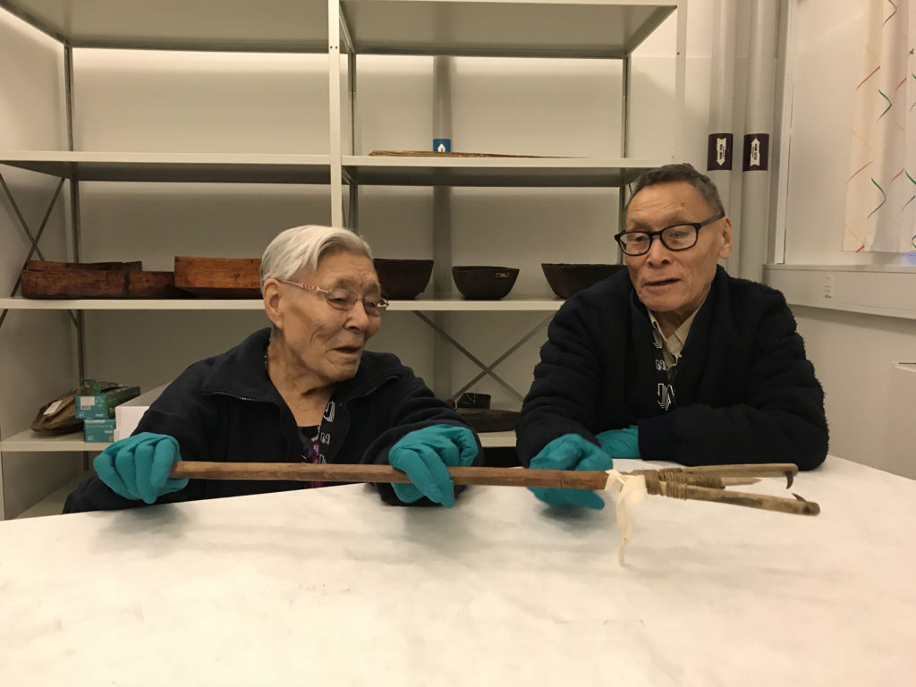 two elders studying traditional artefact