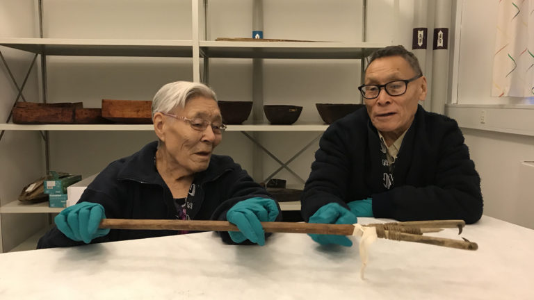 two elders studying traditional artefact