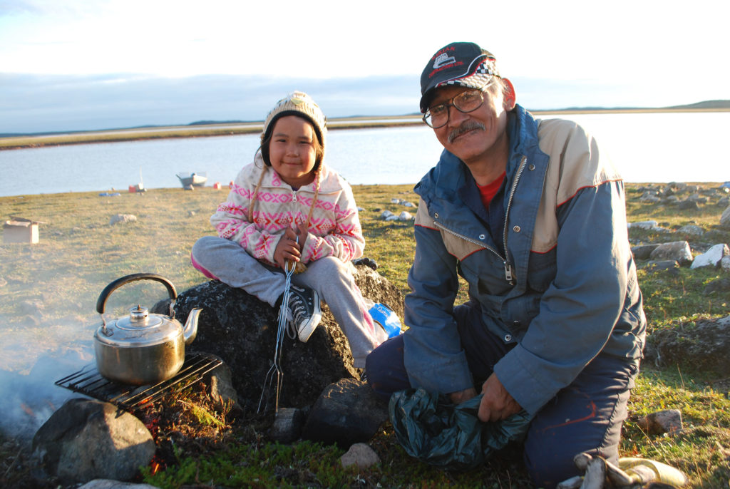 Inuinnait father and daughter cooking outdoor