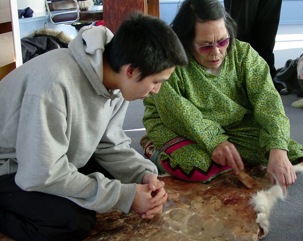 Old woman and young man working on fur