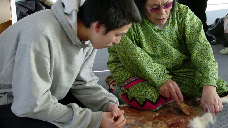 Old woman and young man working on fur