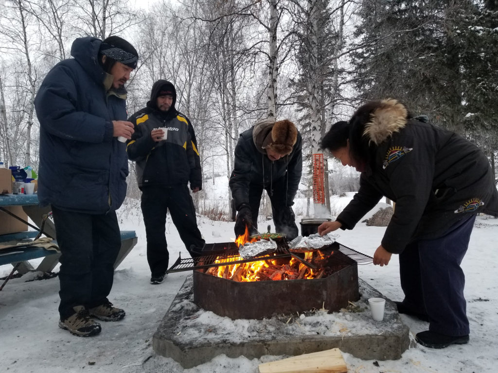 People cooking outdoors over fire