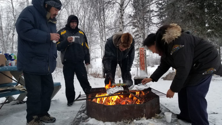 People cooking outdoors over fire