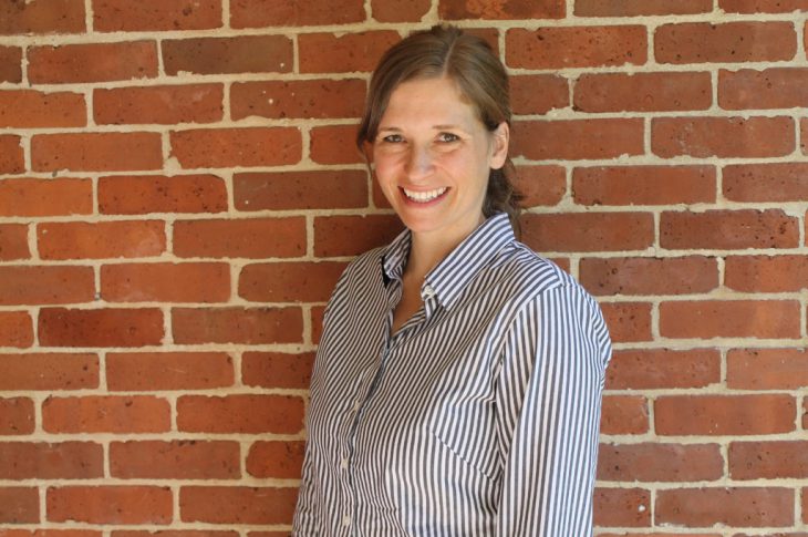 A woman in a striped shirt in front of a red brick wall.